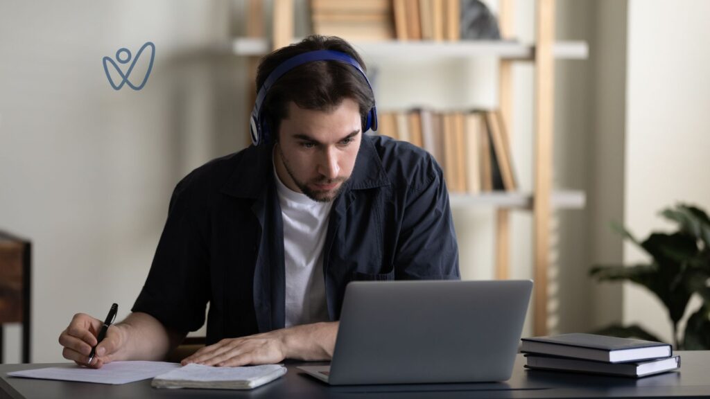 A gentlemen writing and looking at a computer